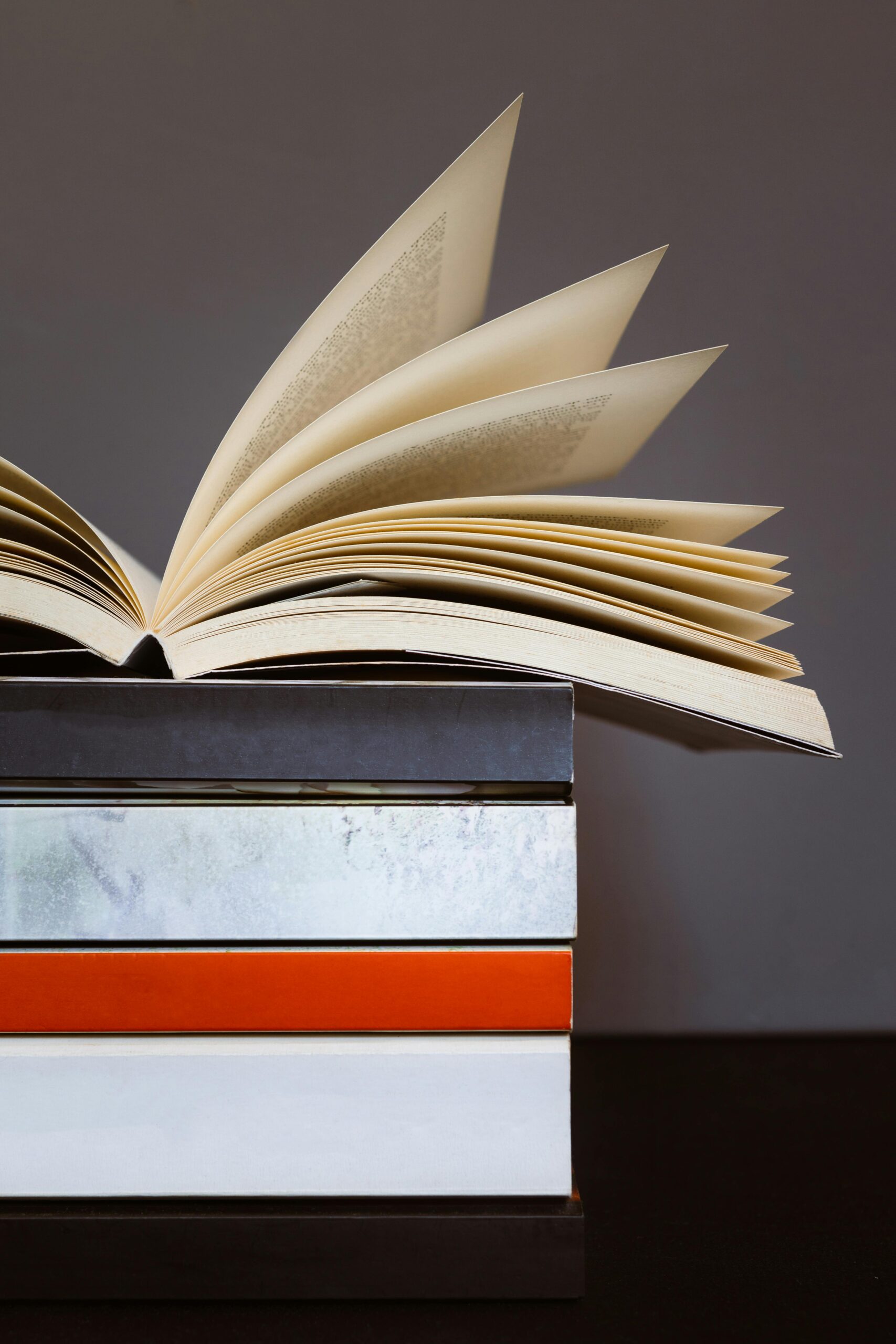 Creative photo of an open book on stacked colorful books, symbolizing learning and literature.